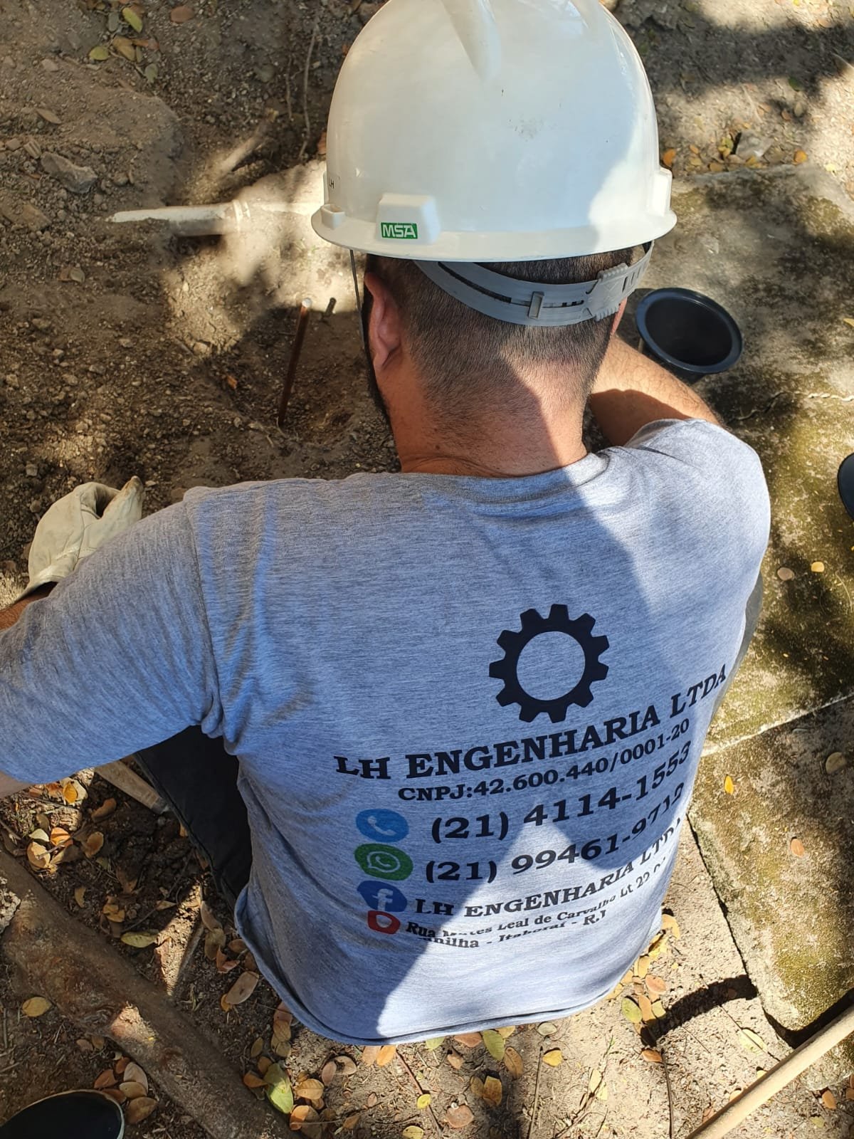 Profissional da LH Engenharia com uniforme e capacete trabalhando junto a uma instalação no solo